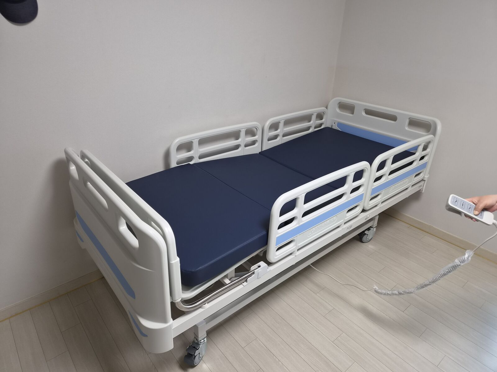 광진 재가복지와 함께 안내하는 복지용구 참고사진 - 안전난간을 올린 전동침대와 리모컨